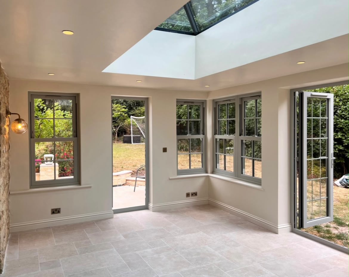 Inside the orangery, with sash windows and French doors open to the garden